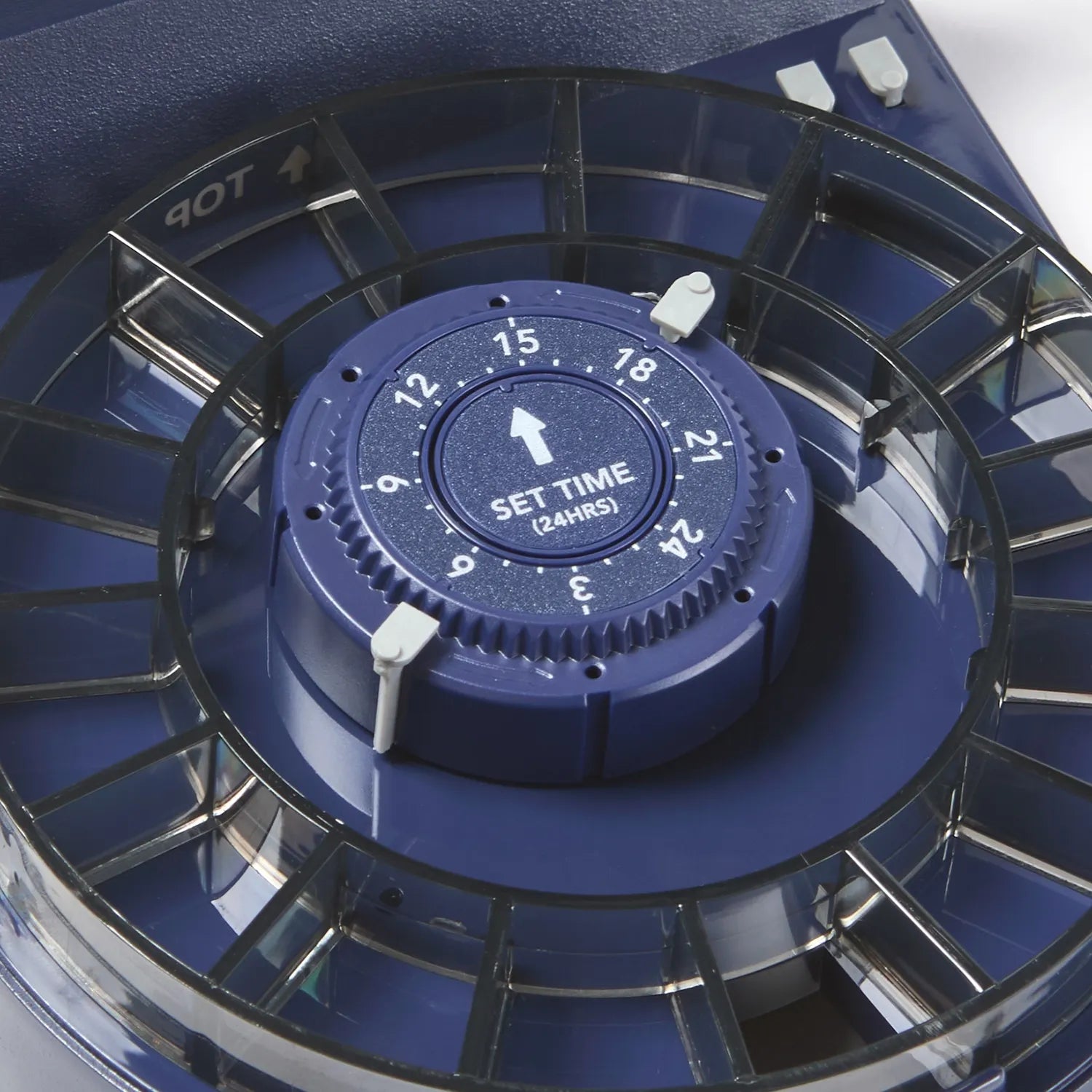 Close-up of a blue timer with a dark coloured plastic food portion ring on a white background