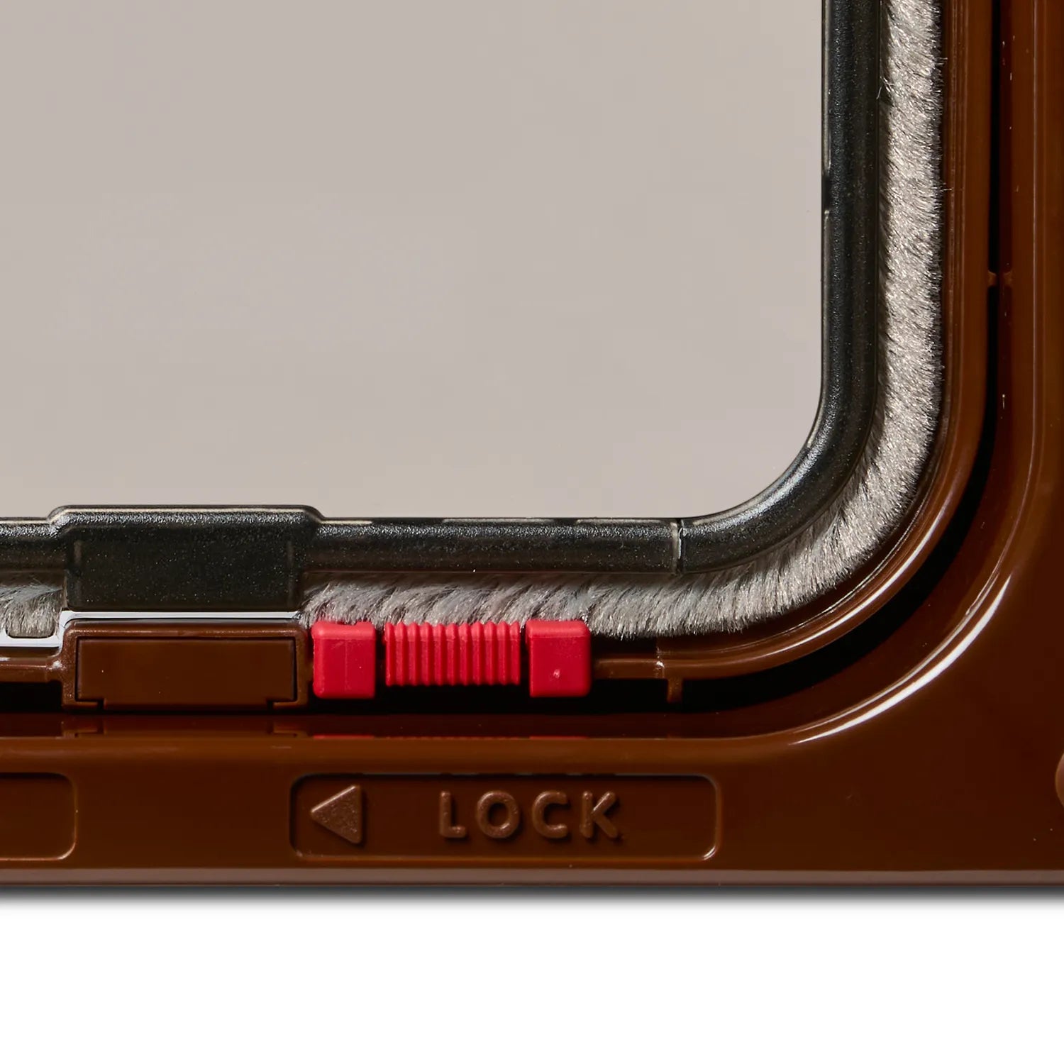 Close-up of a lockable brown cat door frame with a clear flap on a white background