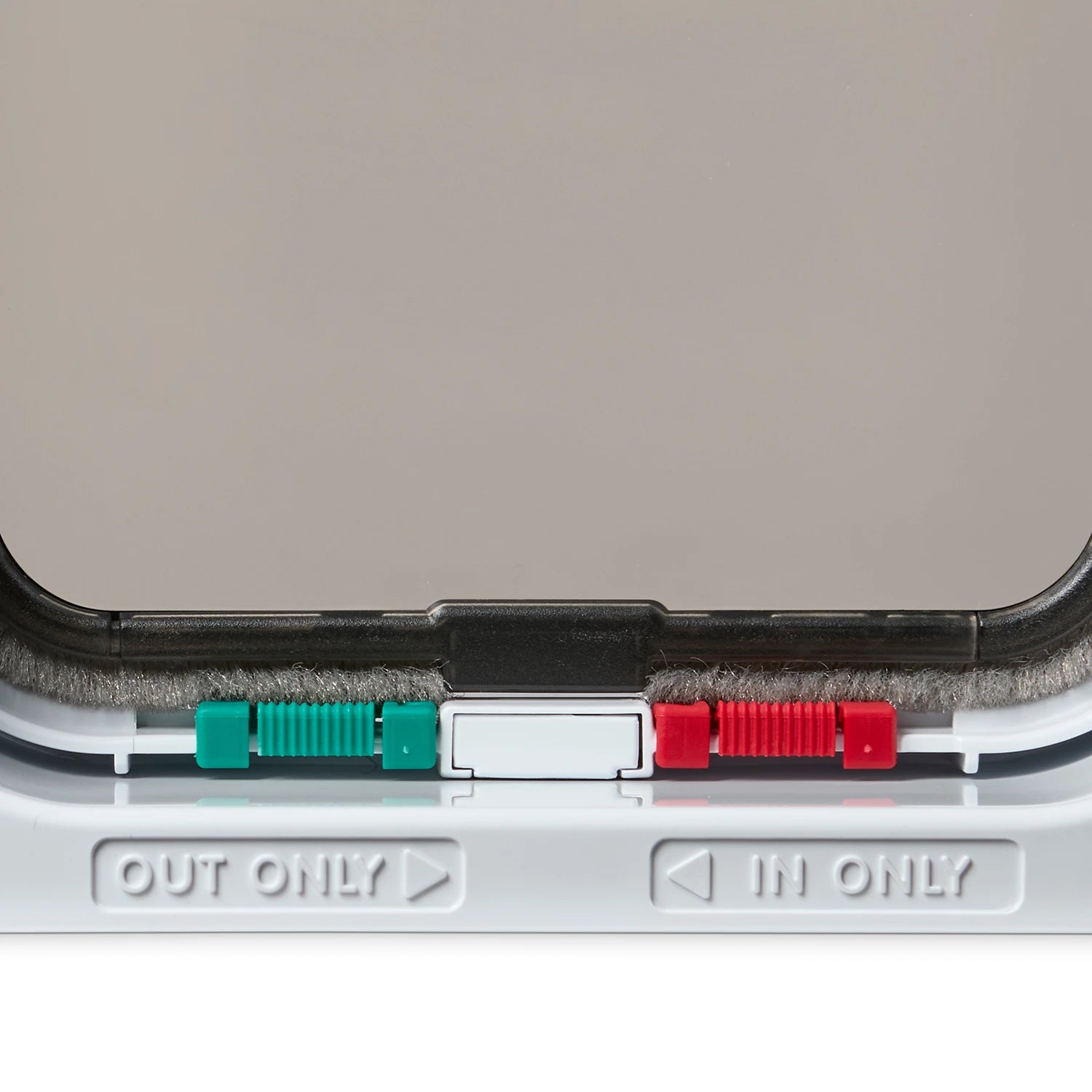 Close-up of the white cat door frame and locks with 'OUT ONLY' and 'IN ONLY' labels on a grey background