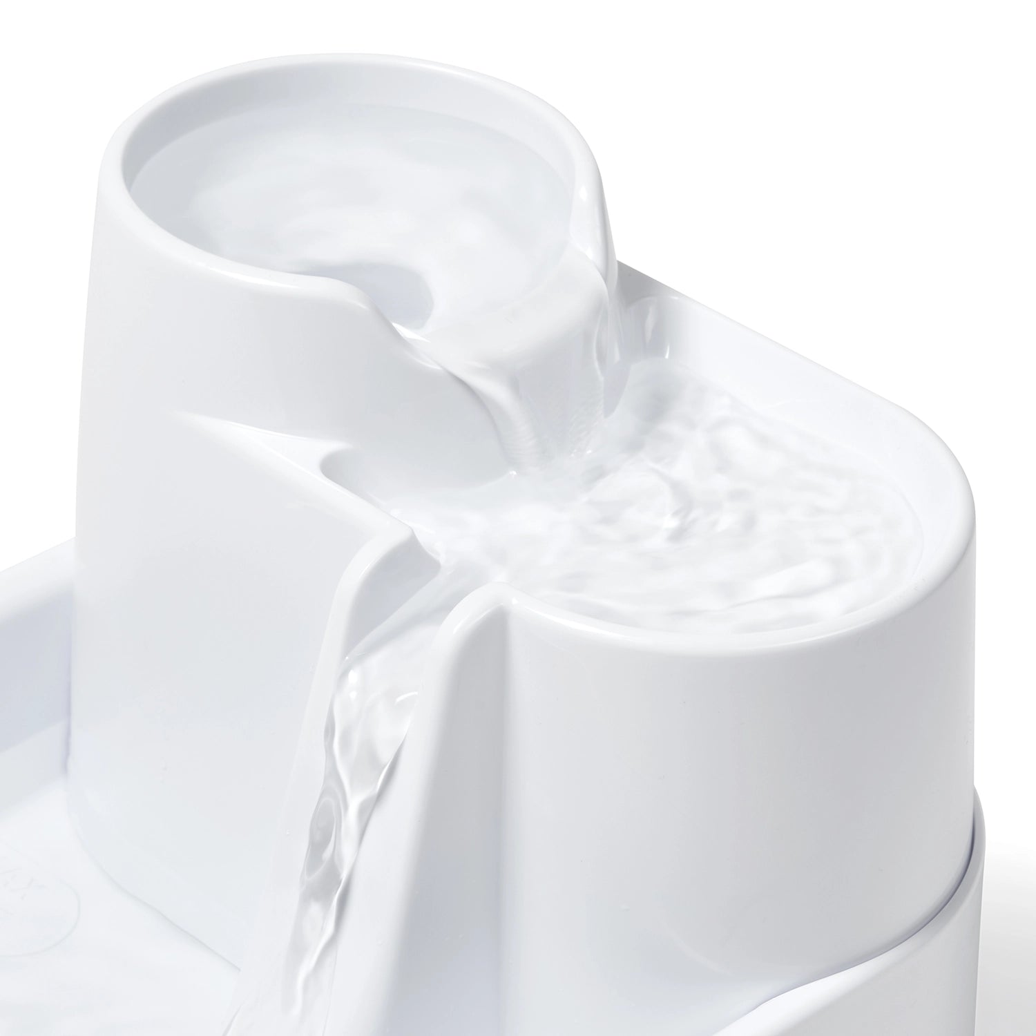 White plastic pet drinking fountain with water flowing down all three levels on a white background