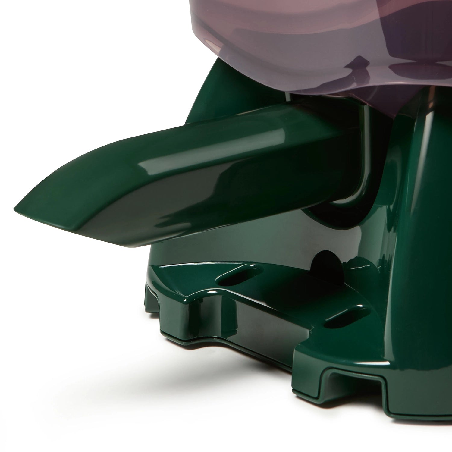 Close-up of a green plastic chute which dispenses dry food for pond fish on a white background