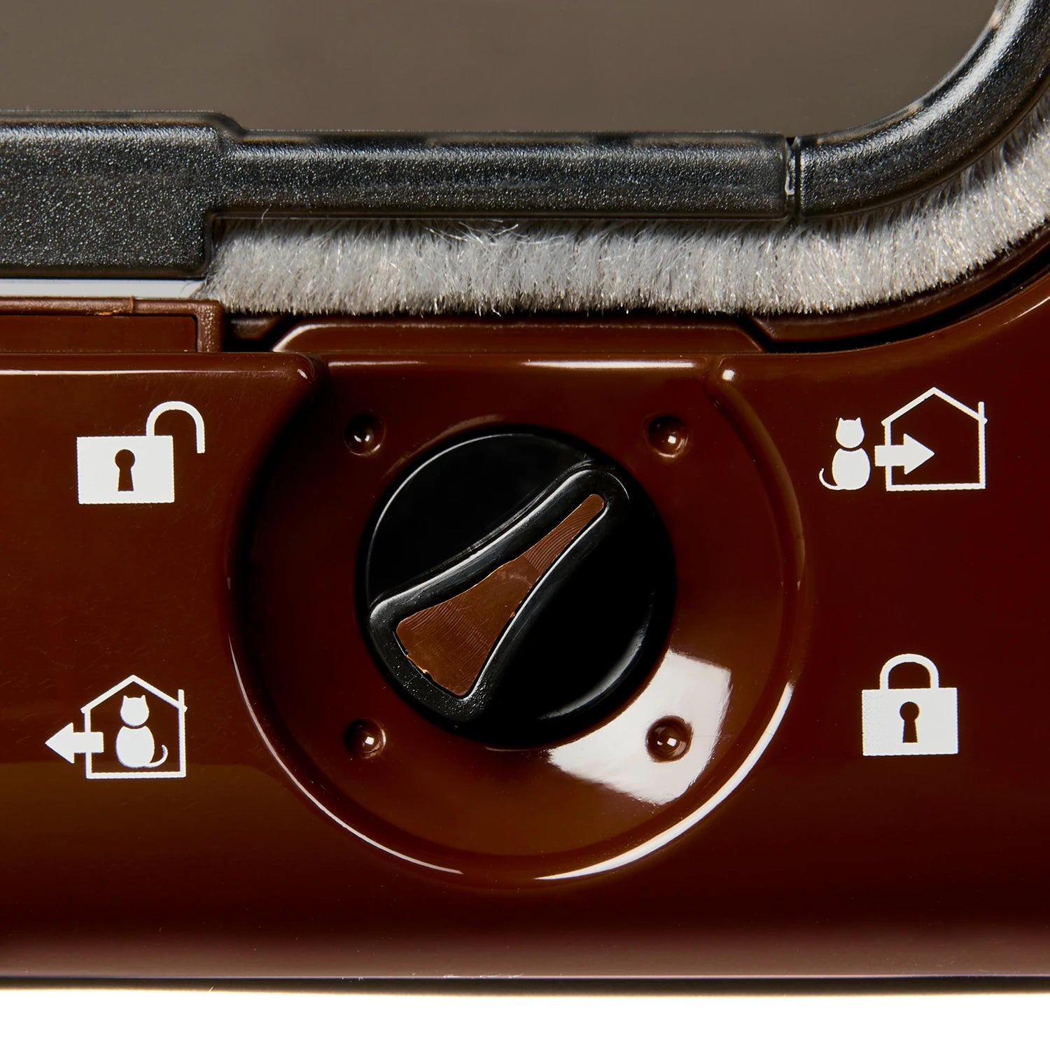 Close-up of the brown, black and white locking dial on the brown microchip activated cat flap, on a white background