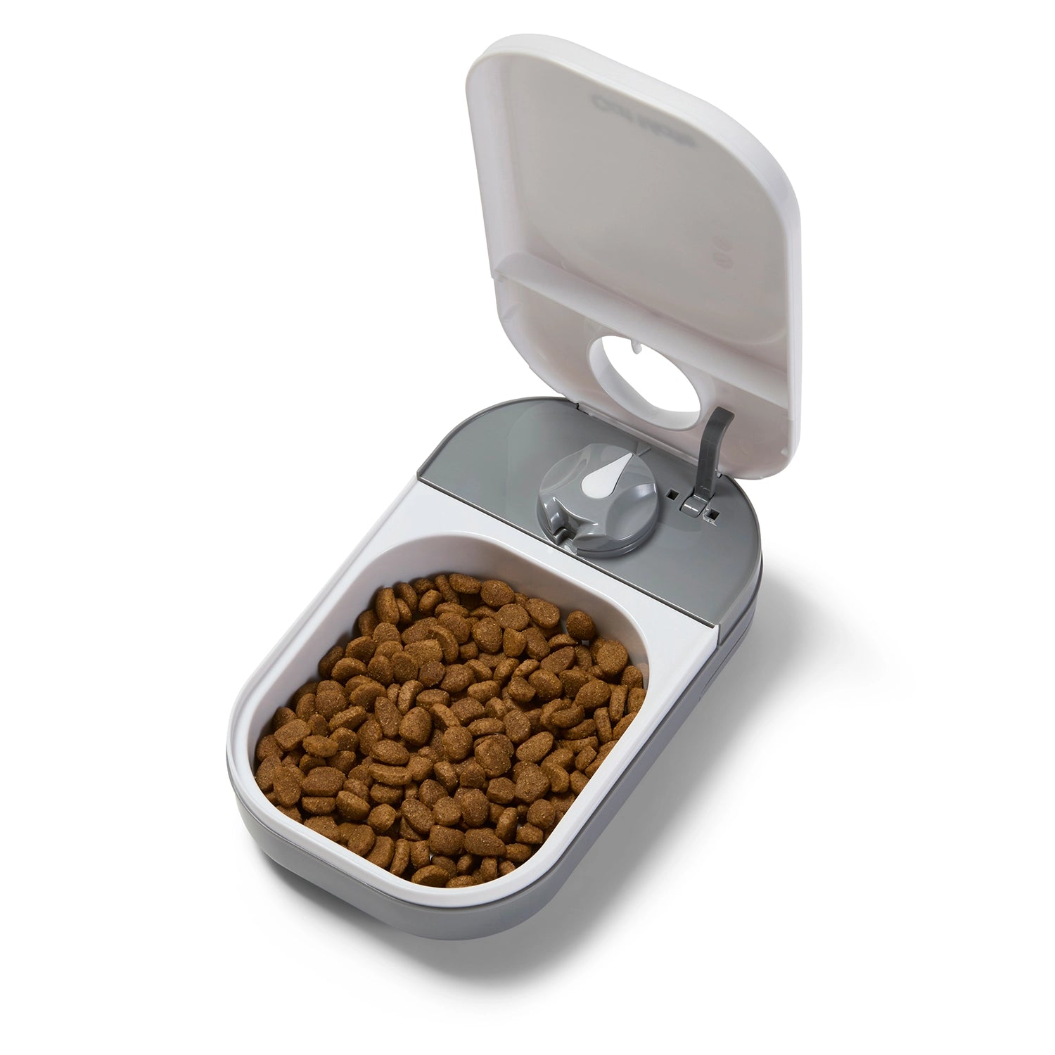 An image of an open pet feeder with the capacity for one meal of dry or wet pet food filled with a portion of dry food on a white background