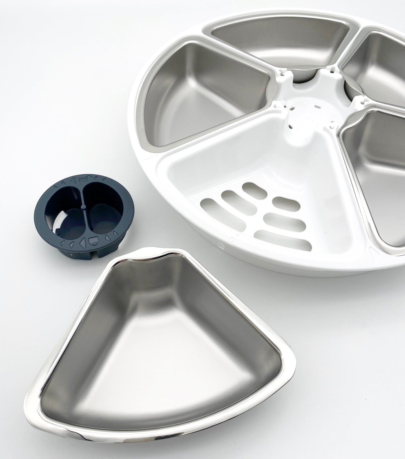 An image of an empty five bowl feeder carousel in the background containing 4 stainless steel bowl inserts, with a dark coloured silicone stopper and a single empty stainless steel bowl insert which completes the carousel in the foreground on a white background