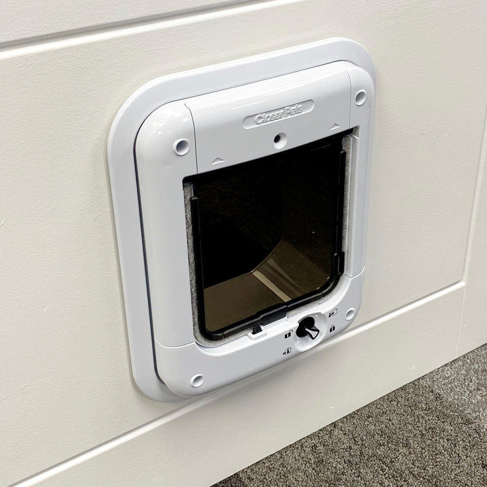A lifestyle image of an white cat flap that has been installed in to a white wall using the white cat flap adapter