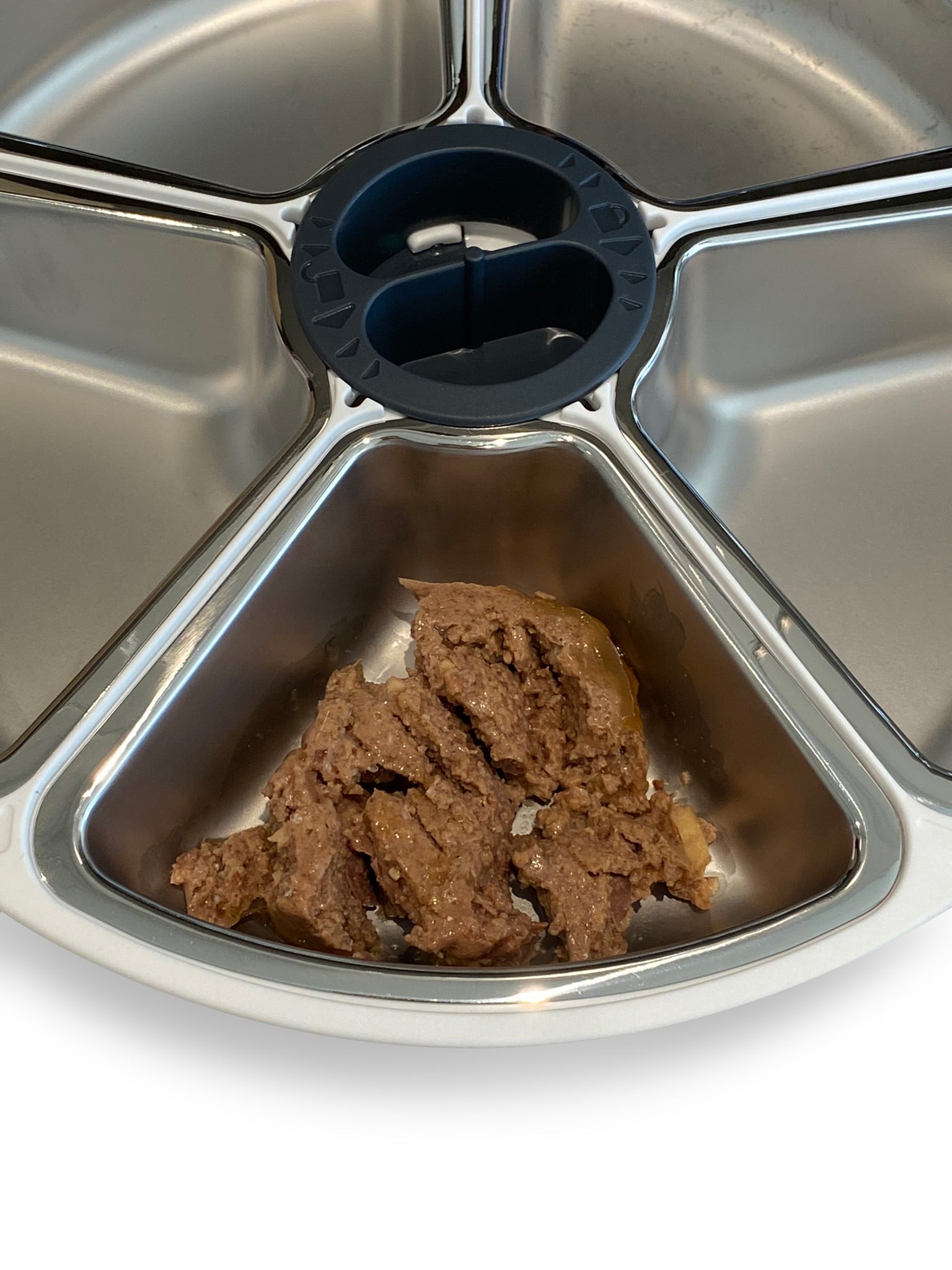 A portion of wet pet food in the stainless steel dish insert as part of the five meal feeder carousel on a white background