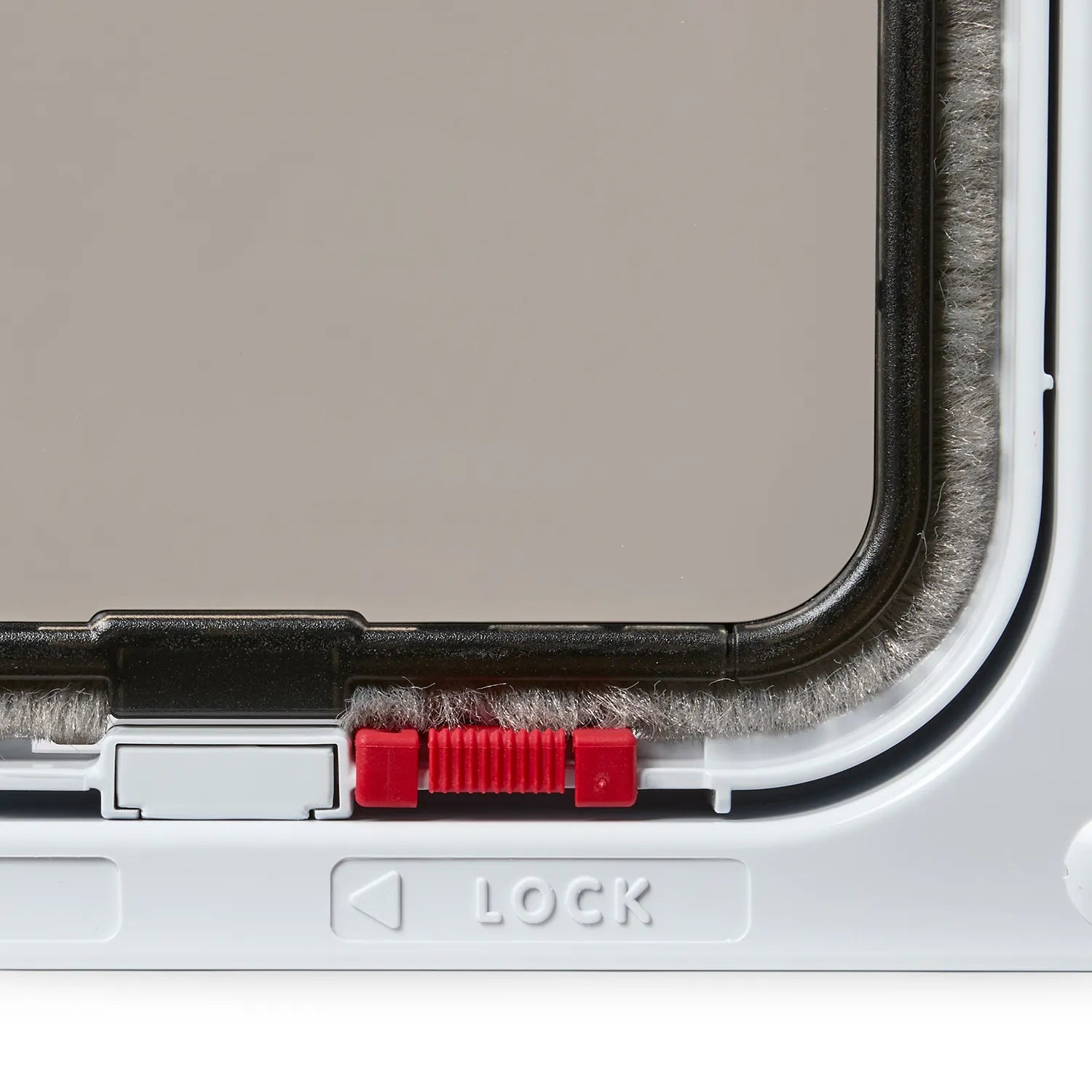 Close up view of a red lock and ''lock'' label written underneath on a white cat cat flap
